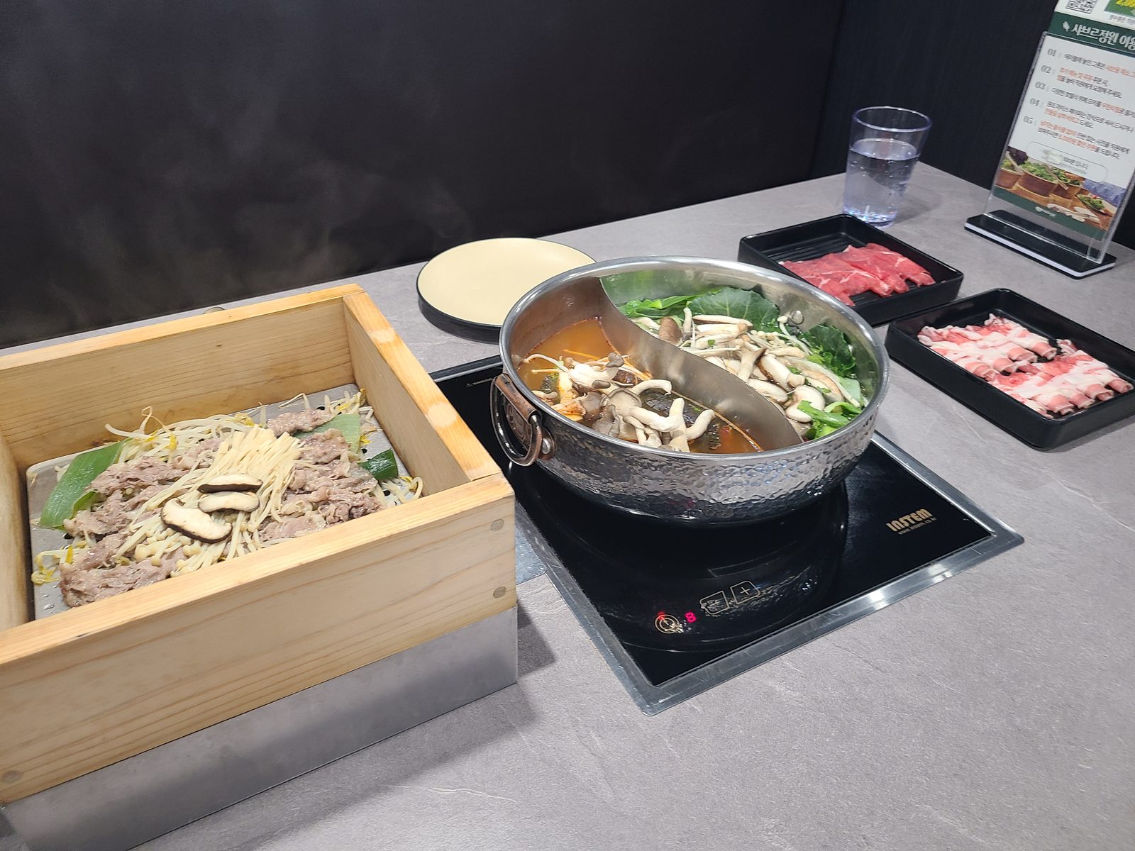 샤브르정원 발산역점 원앙냄비와 편백찜 고기 접시가 놓인 식탁