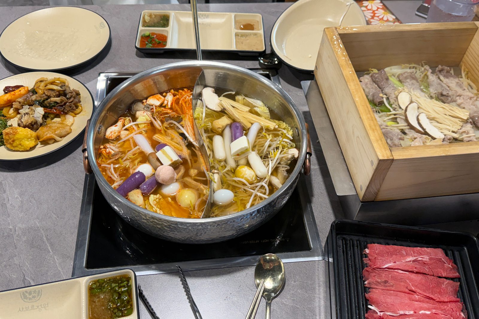 샤브르정원 발산역점 원앙냄비 편백찜 소고기와 뷔페 접시가 놓인 모임 식탁